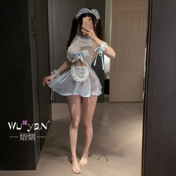 Woman modeling a white, sheer lingerie set with blue bows and a matching headpiece in a bedroom setting.