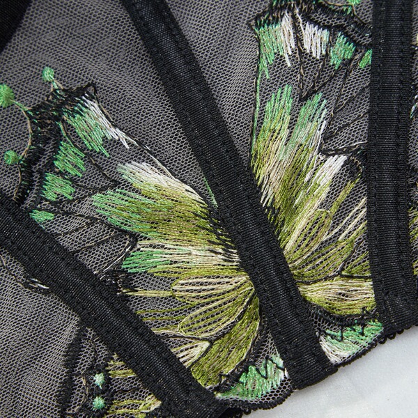 Close-up of green and white floral embroidery on sheer black lace from the sensual lace sheer lingerie set for women.