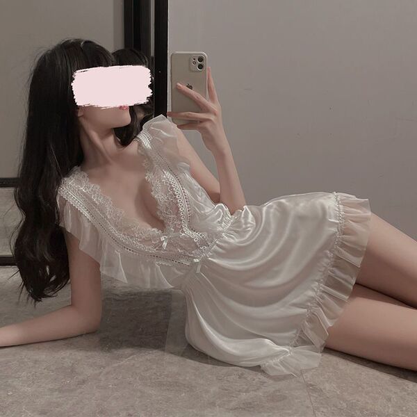 Woman in white lace sleepwear set, posing with phone; sensual floral nightgown & lingerie outfit for youthful elegance.