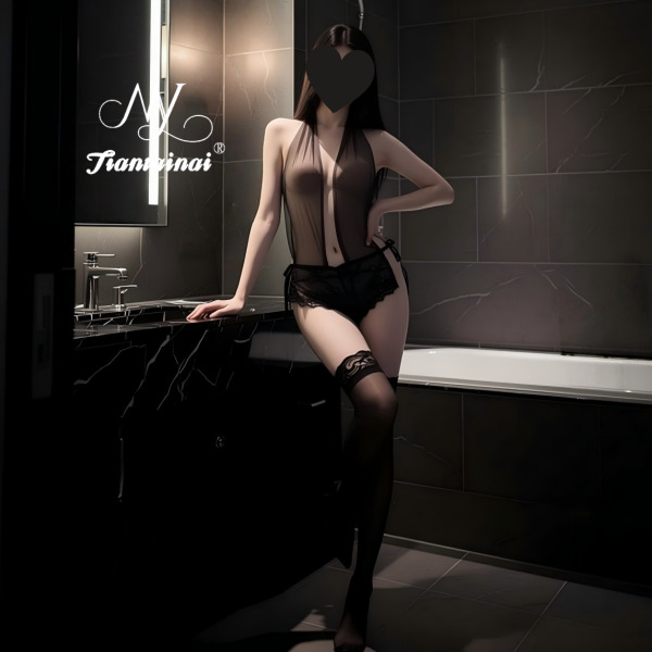 Woman wearing a sexy deep v lace bodysuit with sheer mesh and cross-back design, posing in a modern bathroom setting.