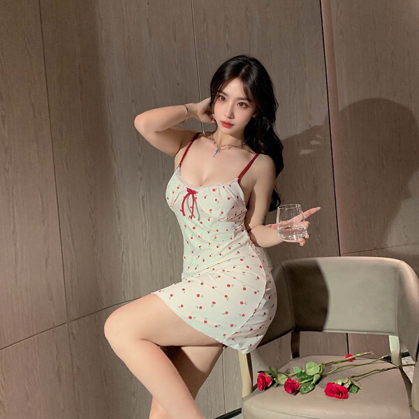 Woman wearing sexy lace babydoll sleep set with built-in pads, holding wine glass beside red roses on chair.