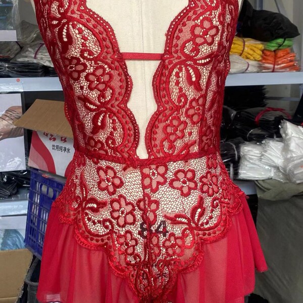Red sheer lace bodysuit with floral embroidery and scalloped edges, displayed on mannequin in lingerie workshop setting.