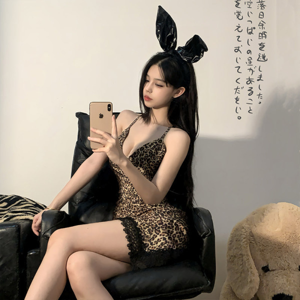 Woman wearing sexy leopard print lingerie set with bunny ears, posing seductively on black leather chair for role play or dat...