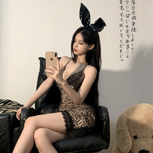 Woman in sexy leopard print lingerie set with bunny ears, posing seductively on black chair for role play.