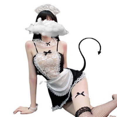Woman wearing black and white sexy maid lingerie set with lace, bow details, tail, and fishnet stockings.