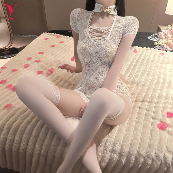 Woman wearing white lace cheongsam lingerie with sheer sleeves and adjustable tie detail, seated on bed with rose petals.
