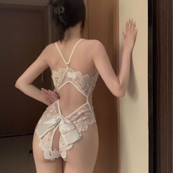 Woman wearing a sexy sheer lace bodysuit with built-in pads, featuring an open-crotch design and delicate floral patterns.