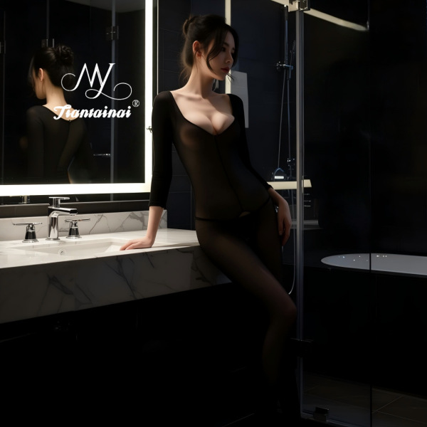 Woman in black sheer open-crotch bodysuit posing in modern bathroom – sexy transparent lingerie outfit for seductive allure.
