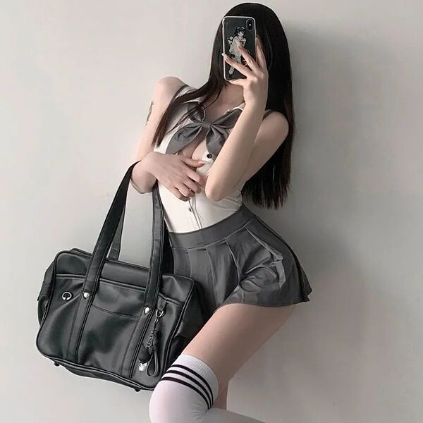 A stylish individual poses with a black leather bag, wearing a white top with a bow tie and a gray pleated skirt, embodying a...