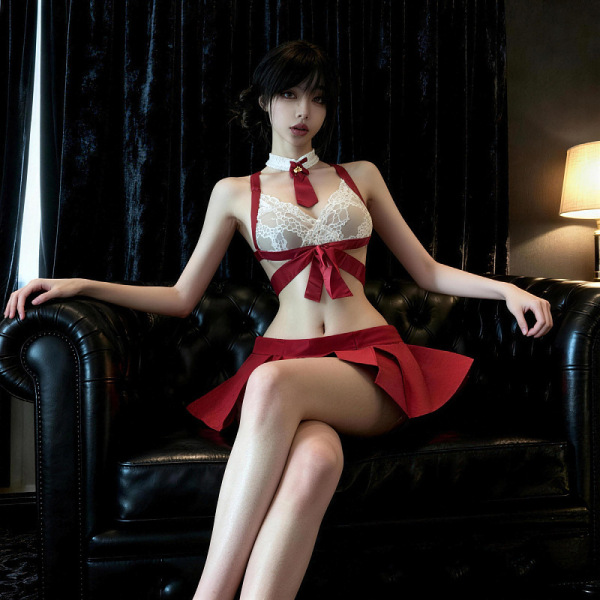 Woman in red pleated skirt set with lace top and bell choker, seated on black leather couch.