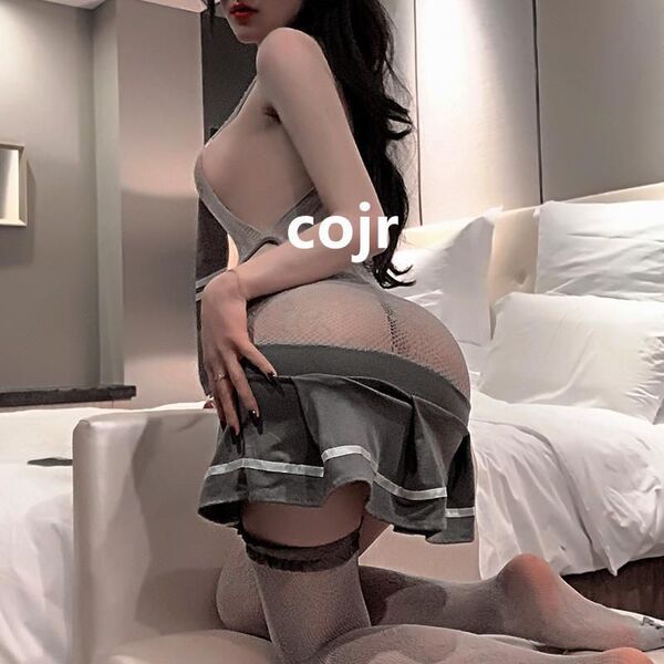 Woman in sexy student jk uniform set with lace bodysuit and sheer stockings, posing seductively on bed.