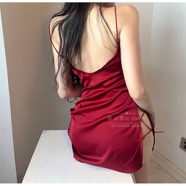 Woman wearing a red silky sleep dress with side cutouts and tie details, showcasing its elegant and alluring design.