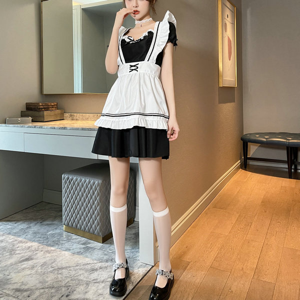A woman models a black and white maid outfit with ruffled sleeves, paired with thigh-high stockings featuring decorative heel...