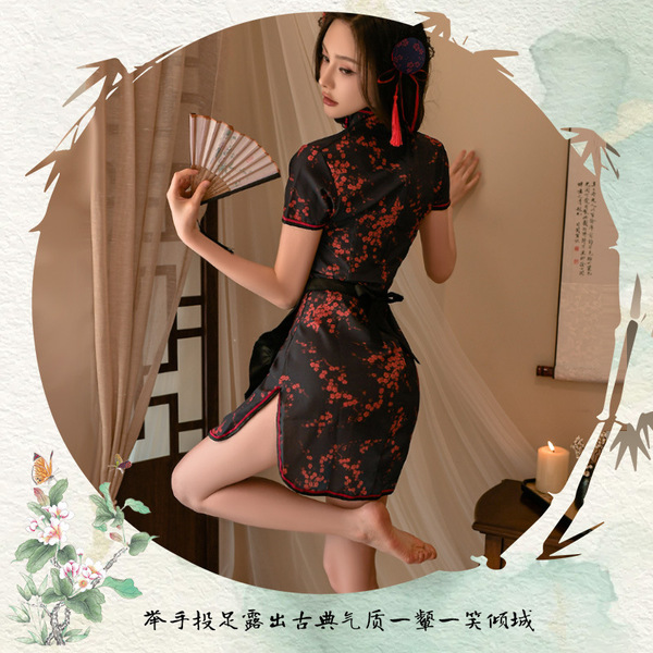 A woman wearing a traditional chinese qipao with floral patterns, holding a fan, poised elegantly indoors.