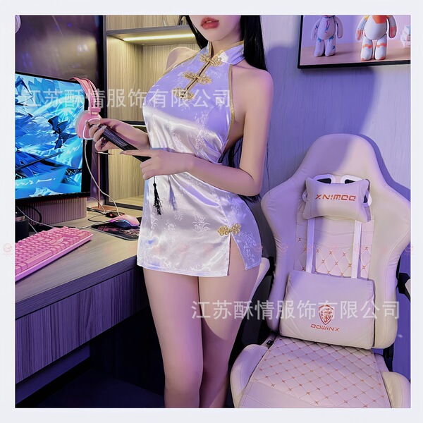 Woman in sultry lace cheongsam sleepwear set playing video game at desk with gaming chair and monitor.