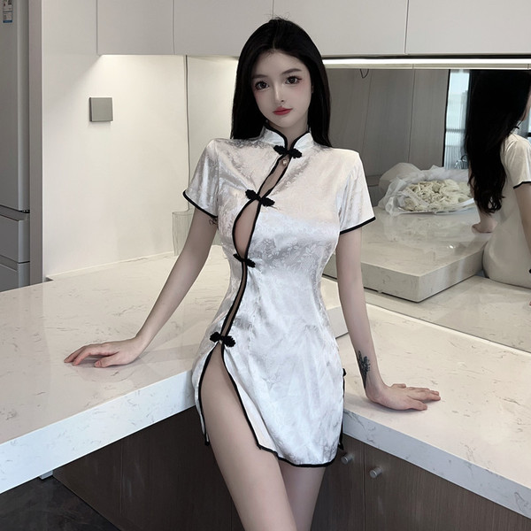 A woman poses elegantly in a chic kitchen, wearing a stylish white cheongsam-inspired dress featuring a high slit and black b...