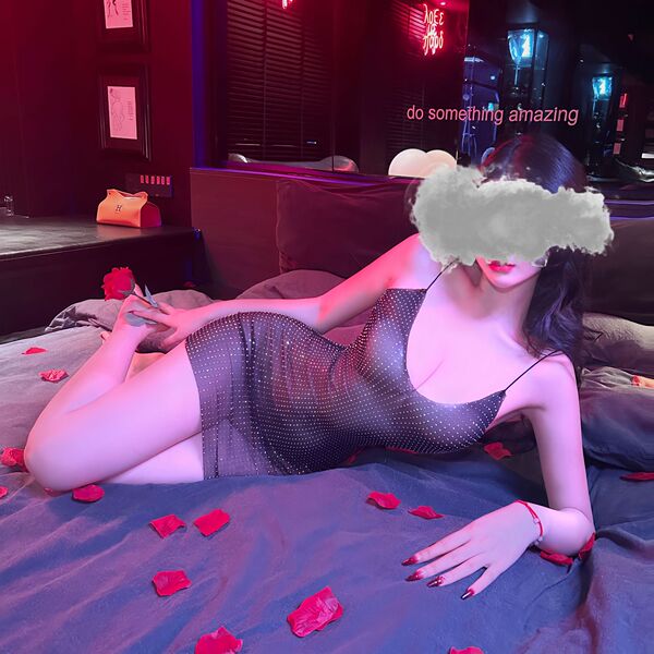 Woman lounging on bed in suoqing sexy v-neck low-cut lace sheer slip dress with full rhinestone embellishment, surrounded by ...