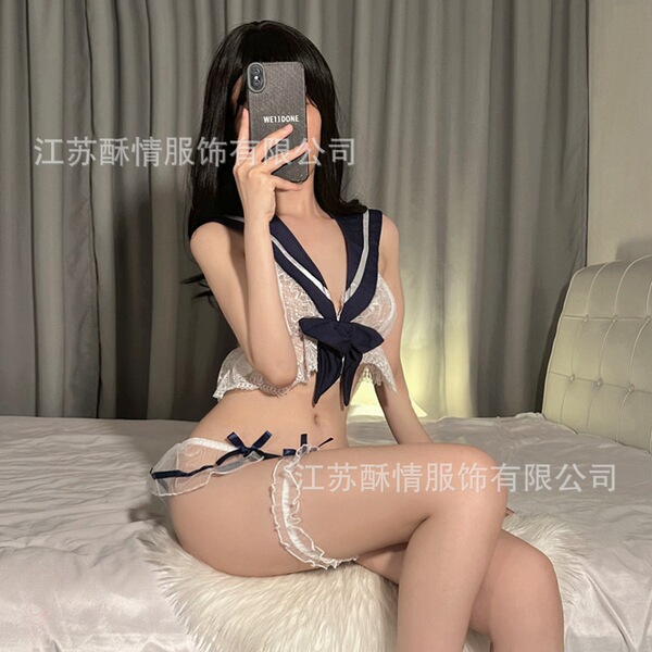 Woman in suqing jk sailor lingerie set posing on bed, featuring lace top with navy bow and matching garter shorts.