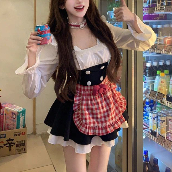 A woman wearing a sweet maid outfit, featuring a white blouse with puffed sleeves, black waistband, and red plaid apron with ...