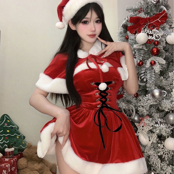 A festive woman poses beside a christmas tree wearing a red velvet robe with white fur trim and a santa hat, perfect for holi...