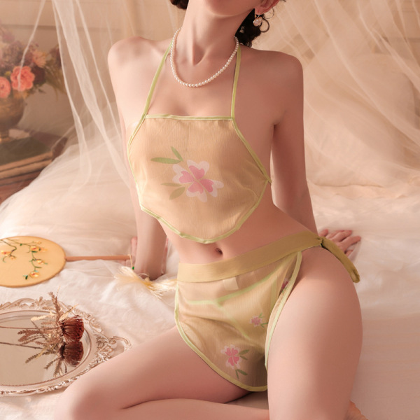 Woman wearing vintage chinese-style belly dance bodice set with floral embroidery, sheer fabric, and pearl necklace, posed on...