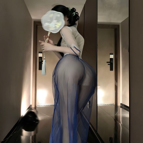 Woman in vintage chinese-inspired lace cheongsam lingerie set with sheer mesh skirt, holding a fan in a hallway.