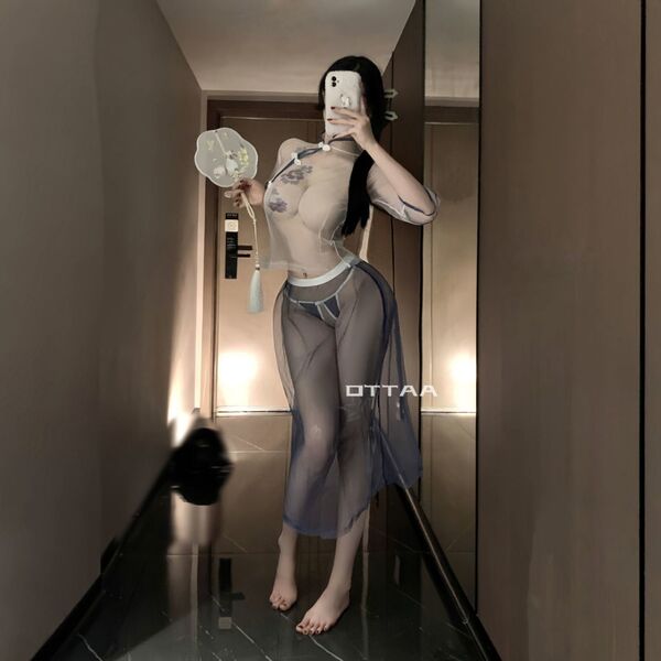 Woman modeling vintage chinese-inspired lace see-through cheongsam lingerie set, holding a fan in a modern hallway.