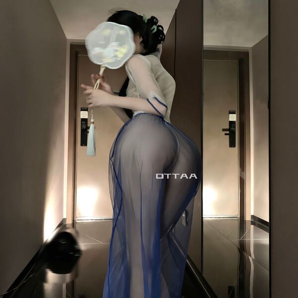 Woman wearing vintage chinese-inspired lace see-through cheongsam lingerie set, holding a fan in a modern hallway.