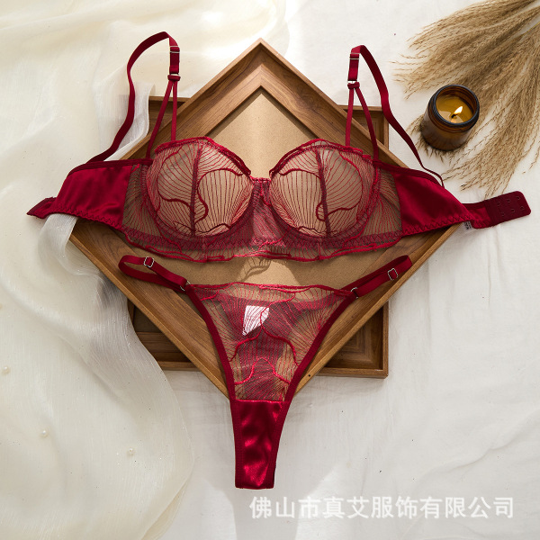 Wine red plus size lingerie set with sheer mesh bra and panty, featuring lace cutouts, displayed on a wooden tray with a cand...