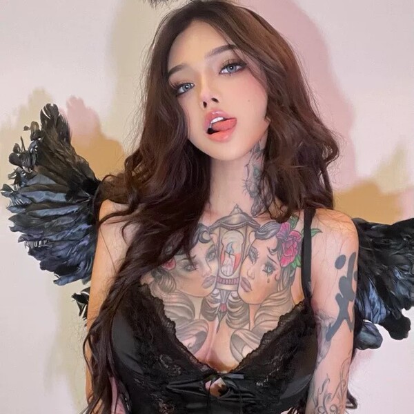 Woman wearing black lace lingerie set with intricate tattoos and angel wings, showcasing elegant and romantic sleepwear desig...