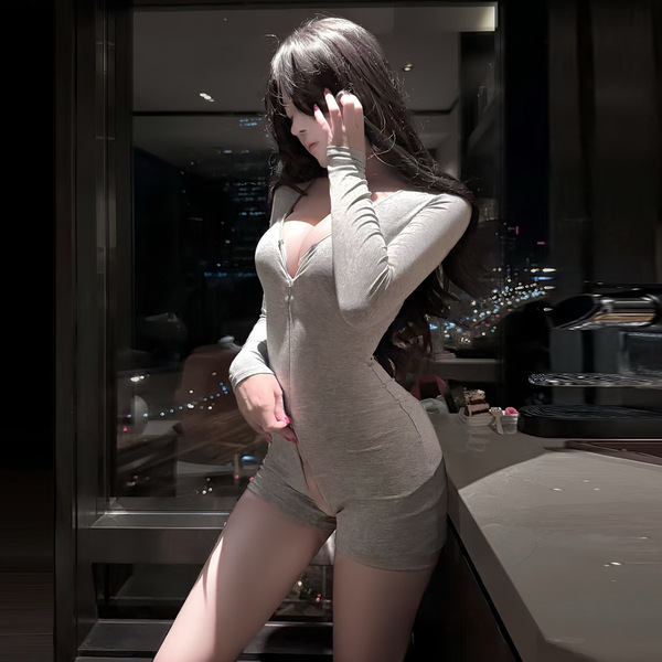 Woman wearing a sleek, form-fitting gray bodysuit with lace detailing, posing by a window at night — perfect for yoga or date...