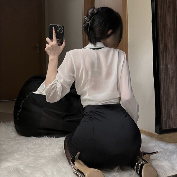 Woman in white blouse and black pencil skirt, part of womens sexy secretary ol costume set, sitting on a fluffy rug.