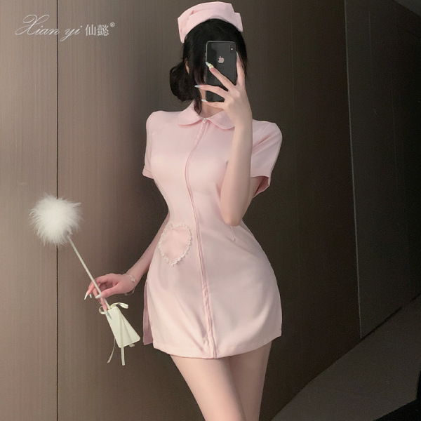 Woman in pink xianyi nurse costume with open-crotch design, holding a fluffy wand, posing for a mirror selfie.