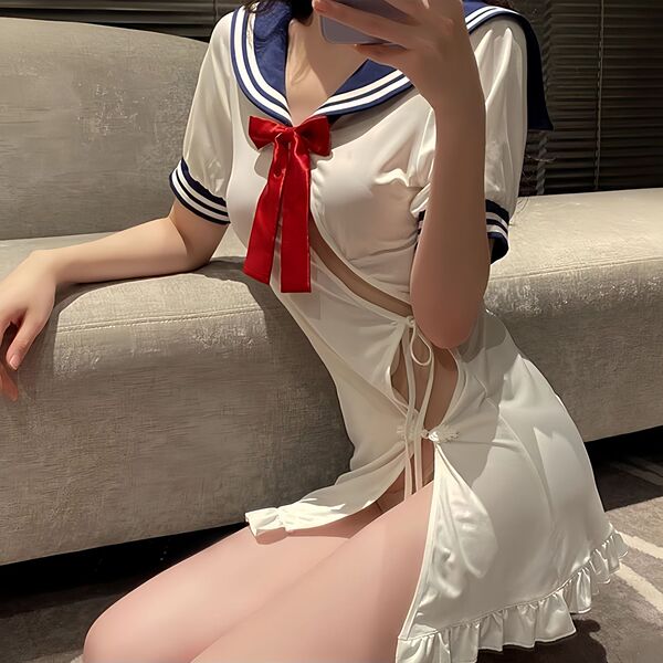Woman in white sailor-style dress with red bow, featuring cutout sides and lace-up detail, posing on a couch.