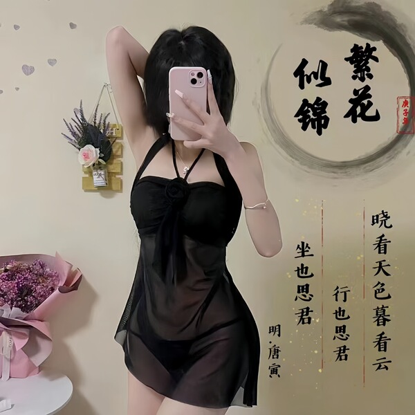 A woman poses with a phone, wearing a black sleep dress. the outfit features halter neck straps and a plunging neckline, idea...