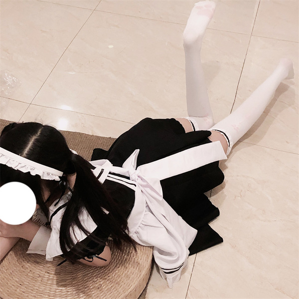 A person wearing a cute japanese lolita cosplay outfit, featuring a black skirt with white accents, sailor-style top, and thi...