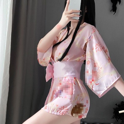 A woman poses with a mirror, wearing a pink japanese cherry blossom-themed kimono-style sleepwear set. the outfit features de...