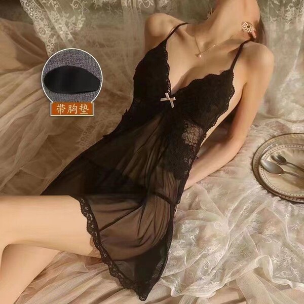Woman wearing black lace chemise with sheer overlay and built-in padding, styled on elegant bedding for luxury sleepwear.