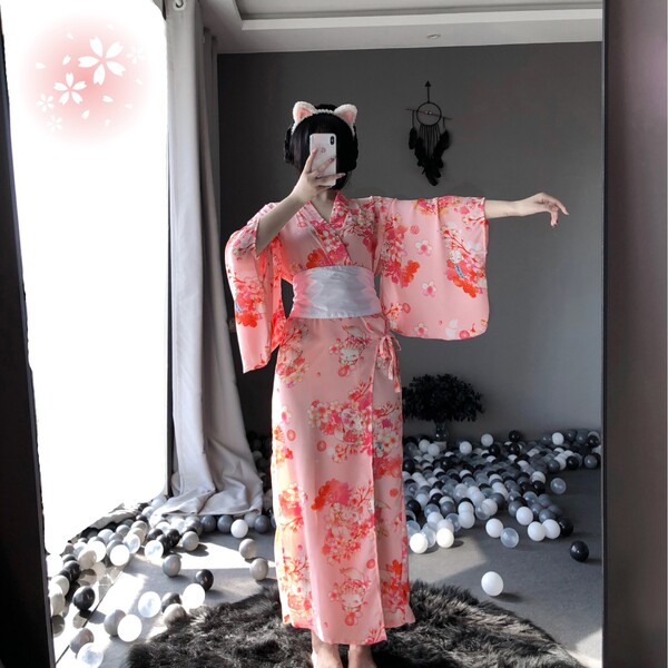 A woman poses in a pink floral japanese kimono-style cat girl lingerie set, featuring elegant long sheer sleepwear with cat e...