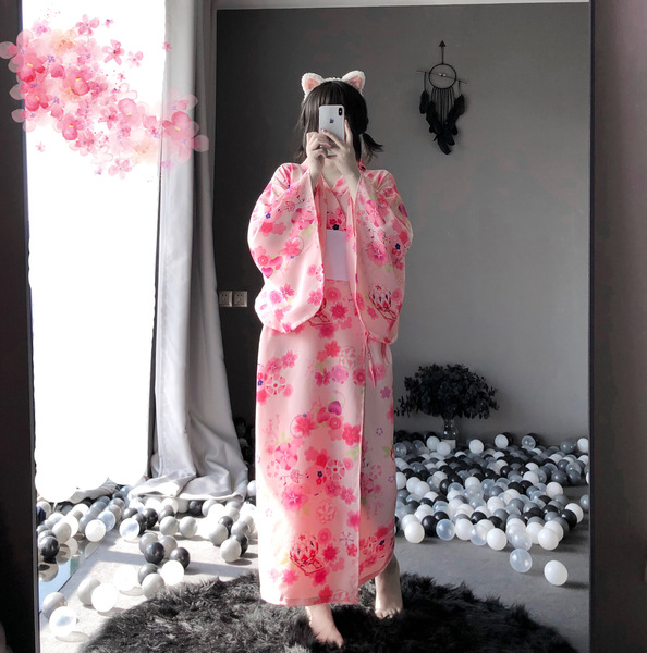A person wearing a pink floral japanese-style kimono, capturing themselves in a mirror surrounded by colorful balls and decor...