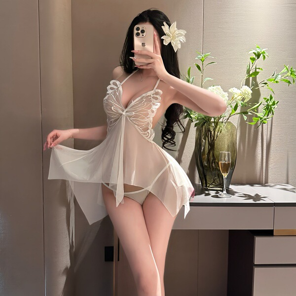 Woman wearing sheer white butterfly halter nightgown with lace details, backless design, and flowing mesh skirt in elegant be...
