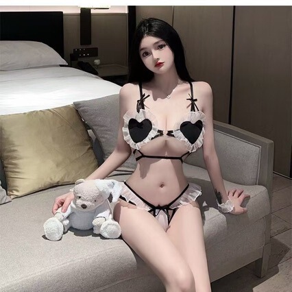 Woman wearing a cute and seductive three-piece maid costume with heart accents, posing on a couch with a plush toy.