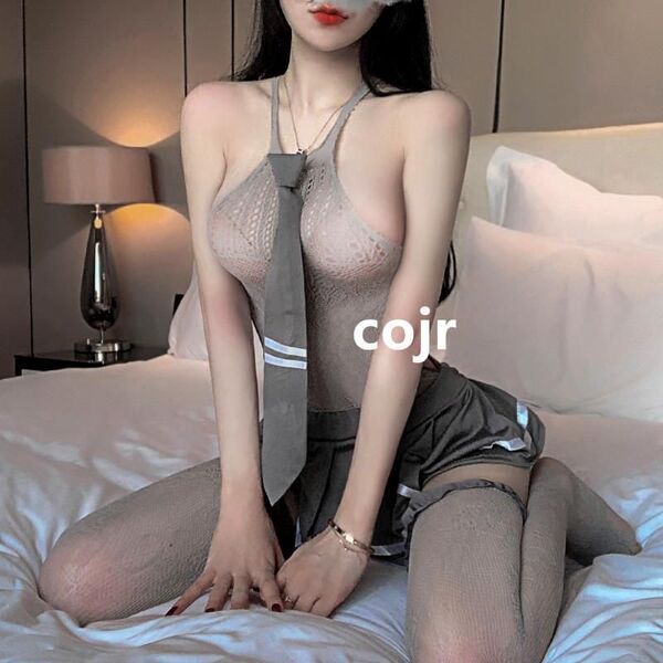 Woman wearing sexy student jk uniform set with lace bodysuit, tie, and sheer stockings on bed.