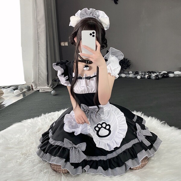A person wearing a black and white maid costume with a cat paw design, sitting on a fluffy rug indoors.