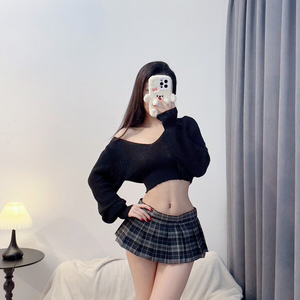 A woman poses with a phone featuring a cute design, wearing a black sheer sweater and a plaid micro skirt, creating a stylish...