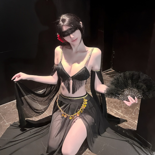 Woman in black fringe lingerie set with sheer skirt, gold coins, feather fan, and blindfold—sensual exotic style for couples.