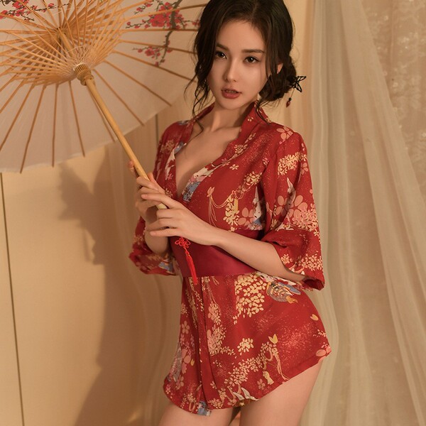 A woman elegantly poses holding a traditional parasol, wearing a vibrant red japanese-style bathrobe adorned with intricate f...