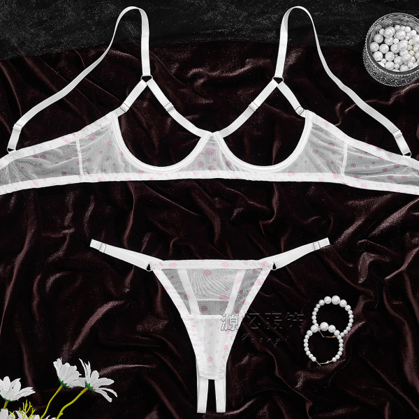 Sheer white bra and panty set with pink polka dots on dark velvet, styled with pearls and flowers.
