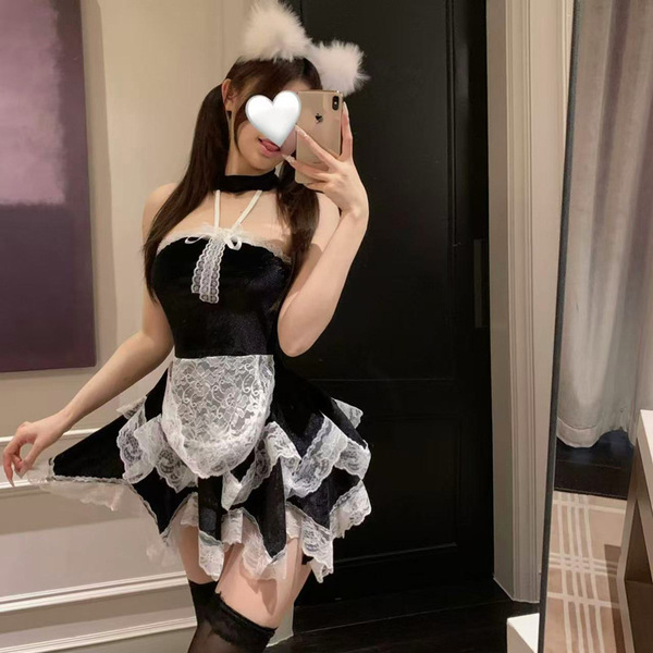 A woman poses in a black and white maid costume with lace details, cat ears, and thigh-high stockings, capturing a playful mo...