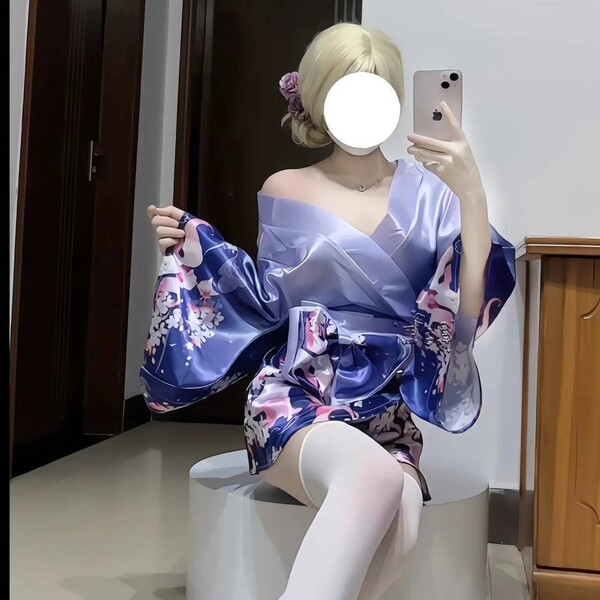A woman poses in a luxurious purple kimono-style outfit adorned with floral patterns, featuring a deep v neckline and flowing...